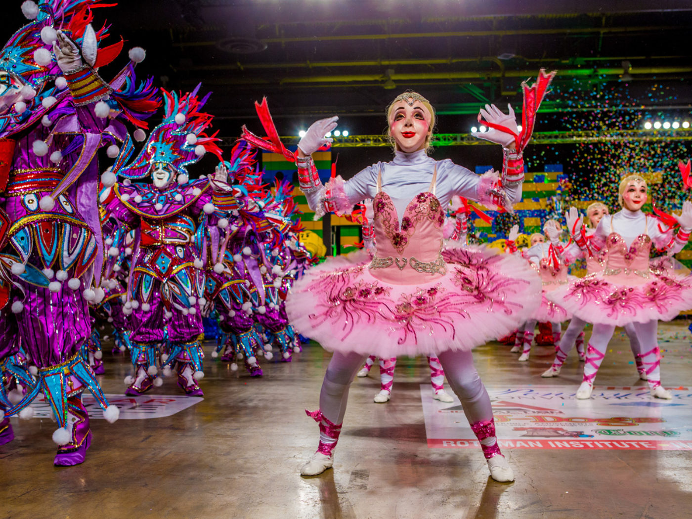 Colorfully costumed Mummers performing under falling confetti